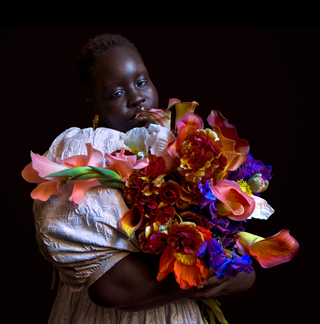 Photo d’une personne tenant un bouquet de fleurs coloré prise par faible éclairage.